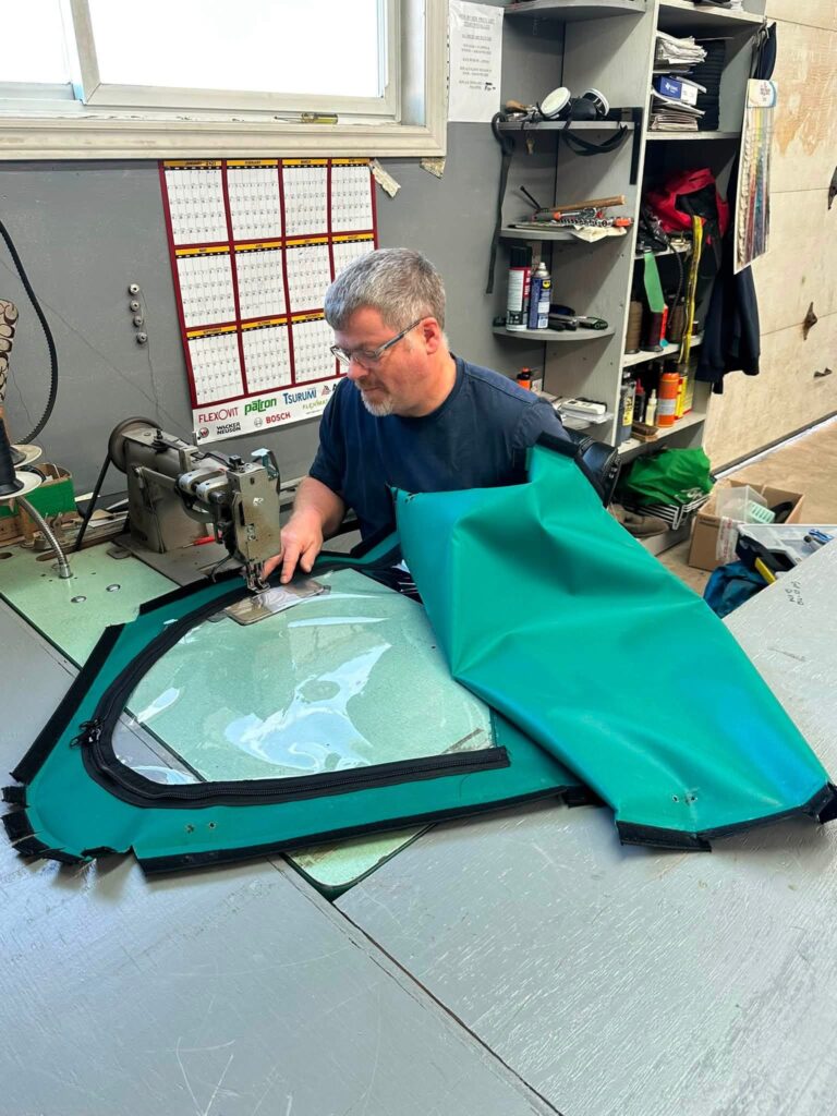 A Byron’s craftsman sewing a custom green side-by-side door with a clear window